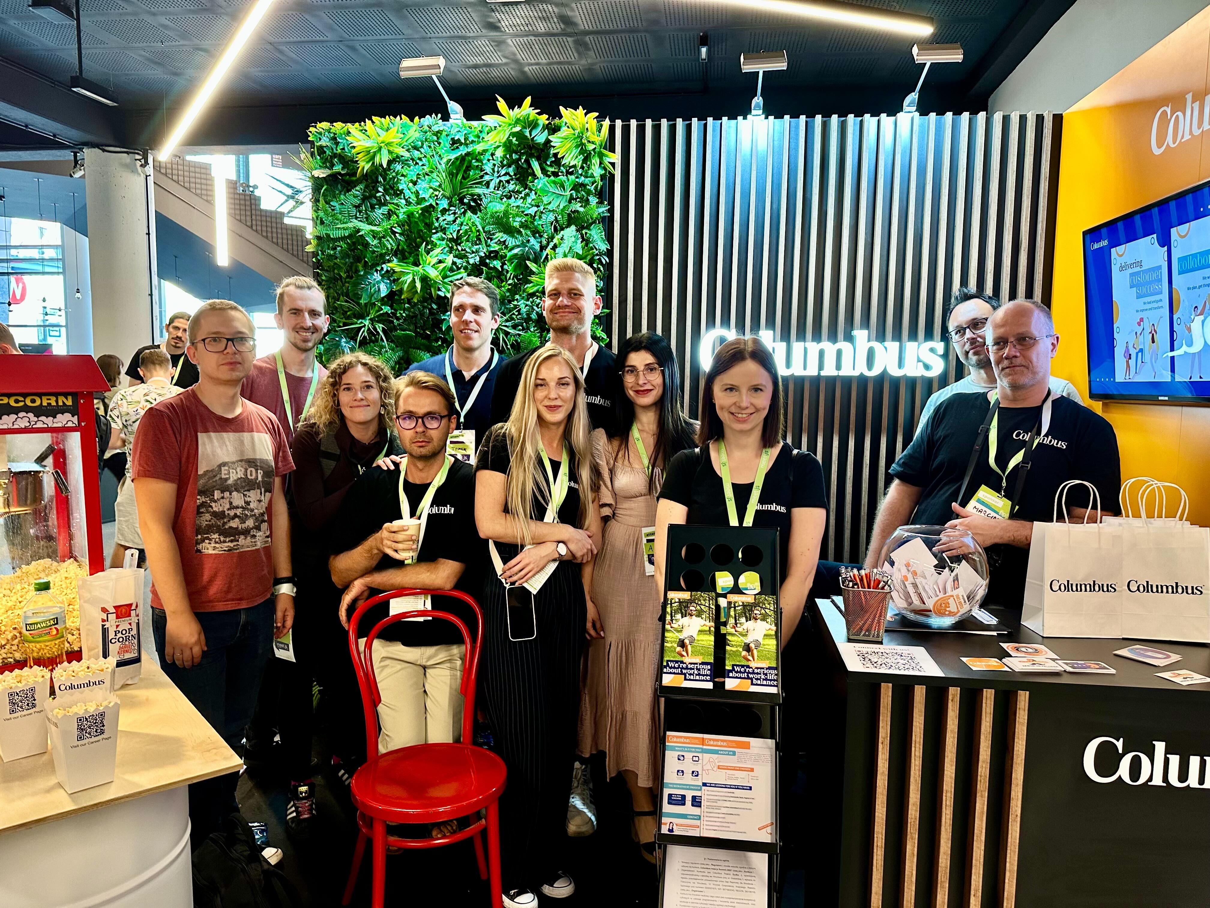 10 columbus employees standing in a columbus booth with popcorn machine and company gadgets